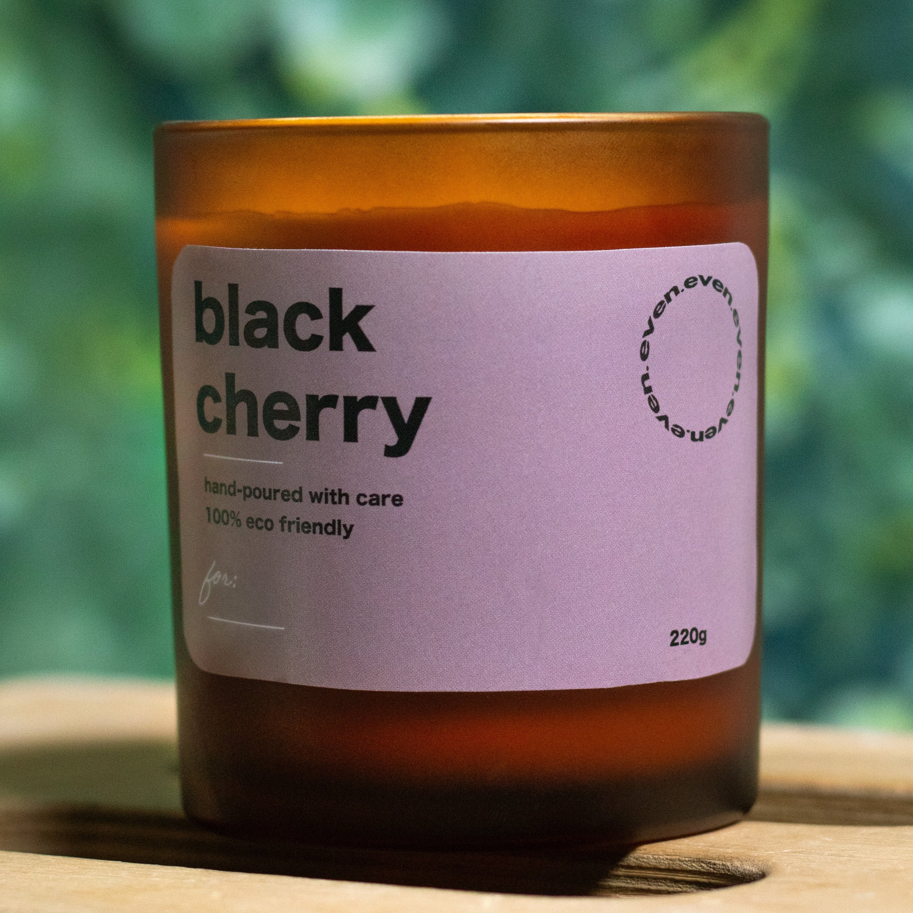 Candle with a 'black cherry' label on a blurred green background.