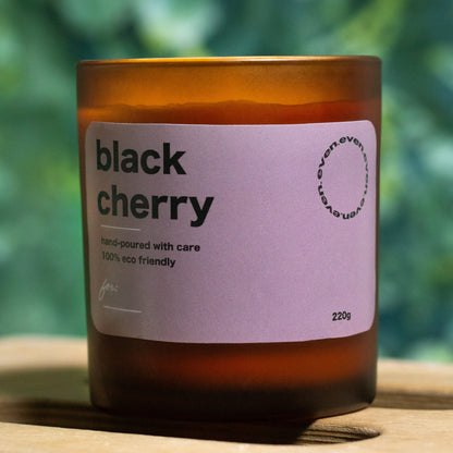 Candle with a 'black cherry' label on a blurred green background.