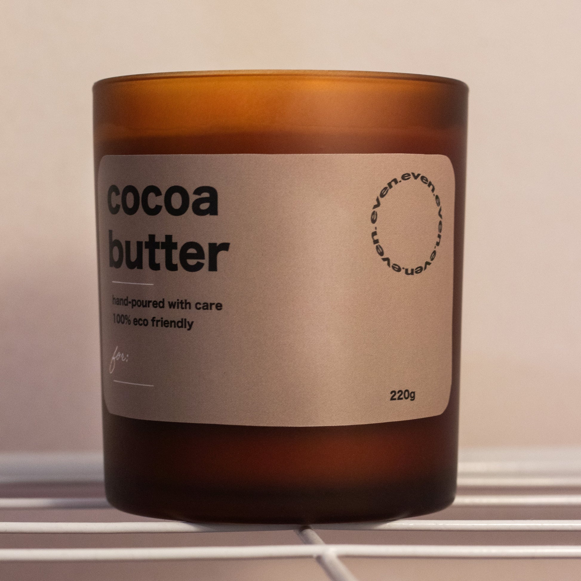 Candle labeled 'cocoa butter' with a brown glass container on a neutral background.