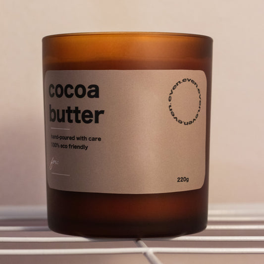 Candle labeled 'cocoa butter' with a brown glass container on a neutral background.
