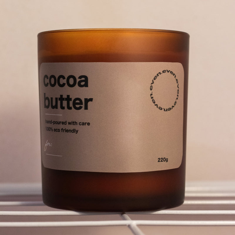 Candle labeled 'cocoa butter' with a brown glass container on a neutral background.