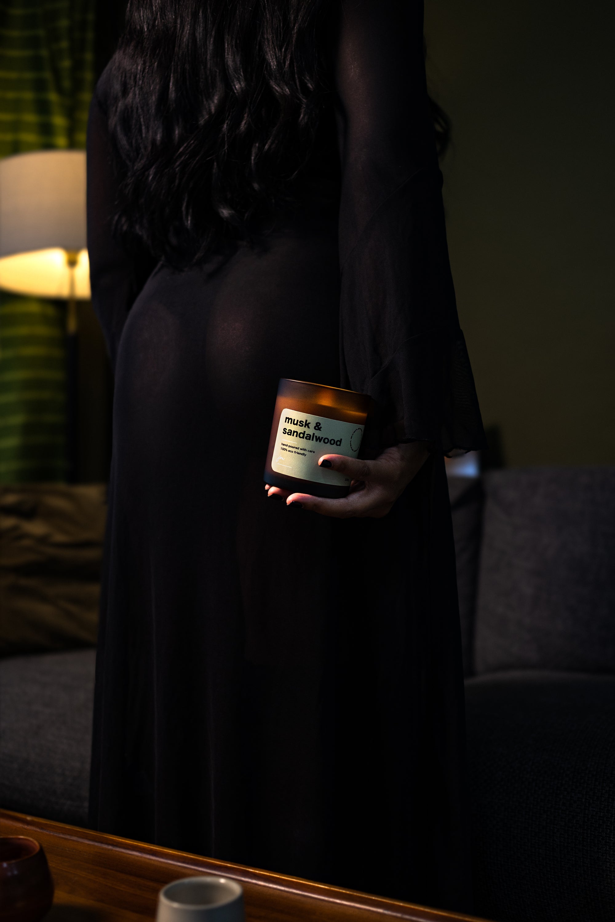 Person holding a candle labeled 'Mood & Movement' in a dimly lit room.