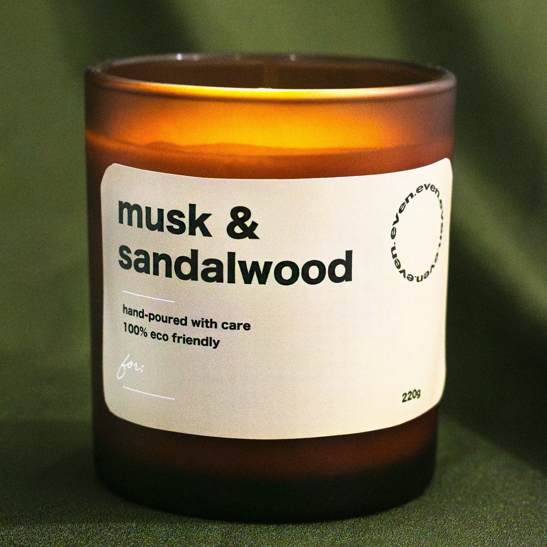Candle with 'musk & sandalwood' label on a green background